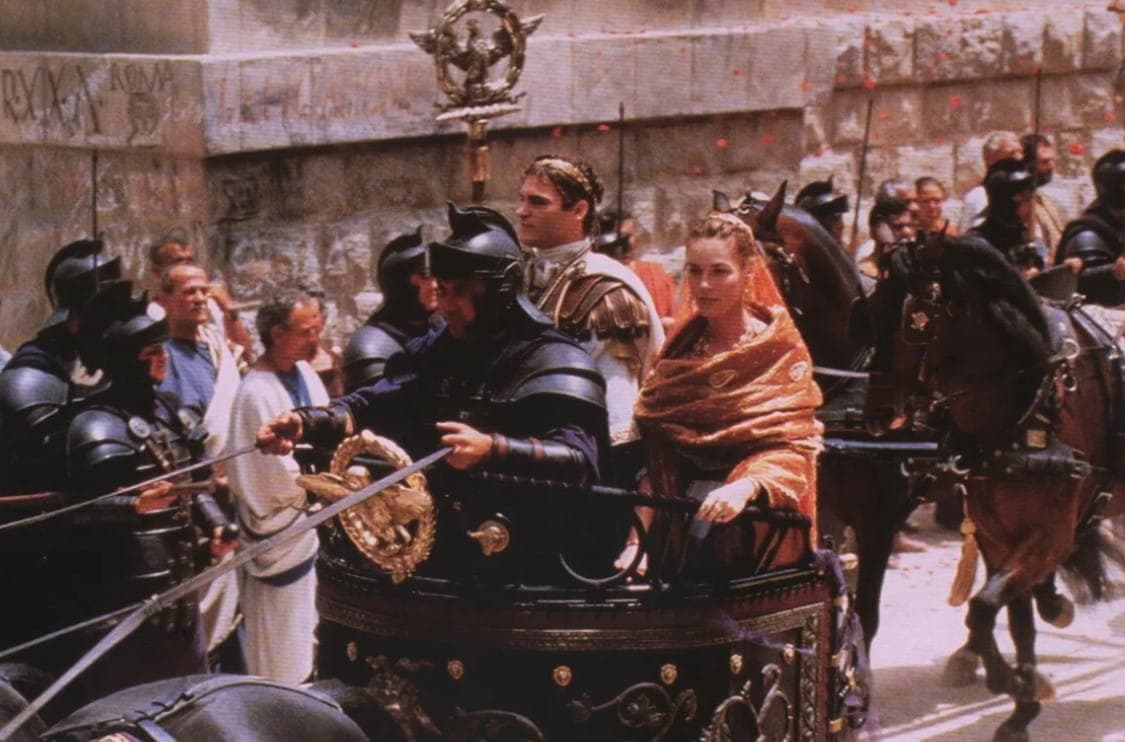 Коммод едет по улицам Рима в сопровождении гвардии. В левом верхнем углу фото - народное настенное творчество, попавшее в кадр. Кадр из фильма "Гладиатор". Scott Free Productions, Red Wagon Entertainment, 2000